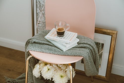 Pink chair with a coffee and books on top